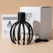 Black head massager with packaging and user manual on a light background