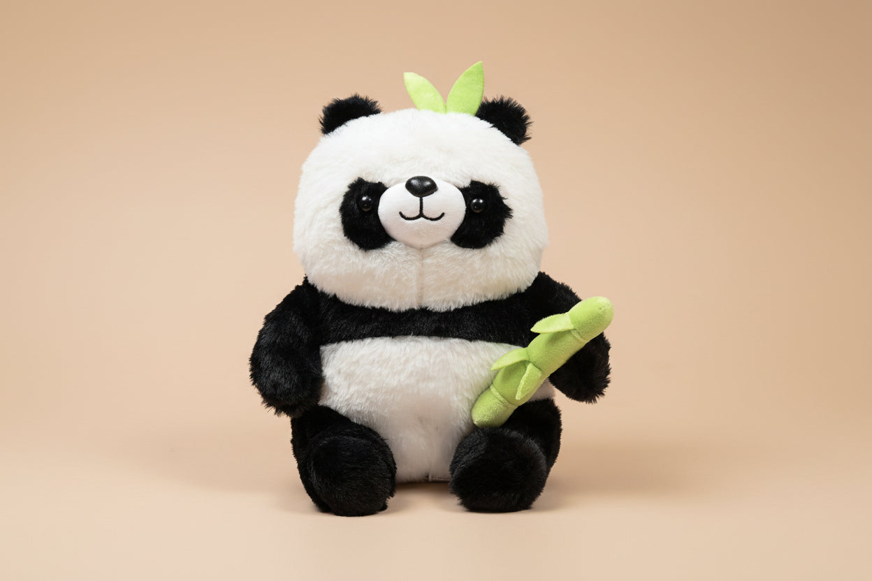 Plush panda toy holding a bamboo stick on a white background