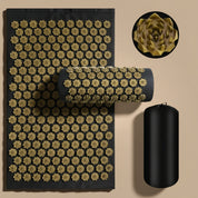 Acupressure mat with gold needles and black roller on a gray background