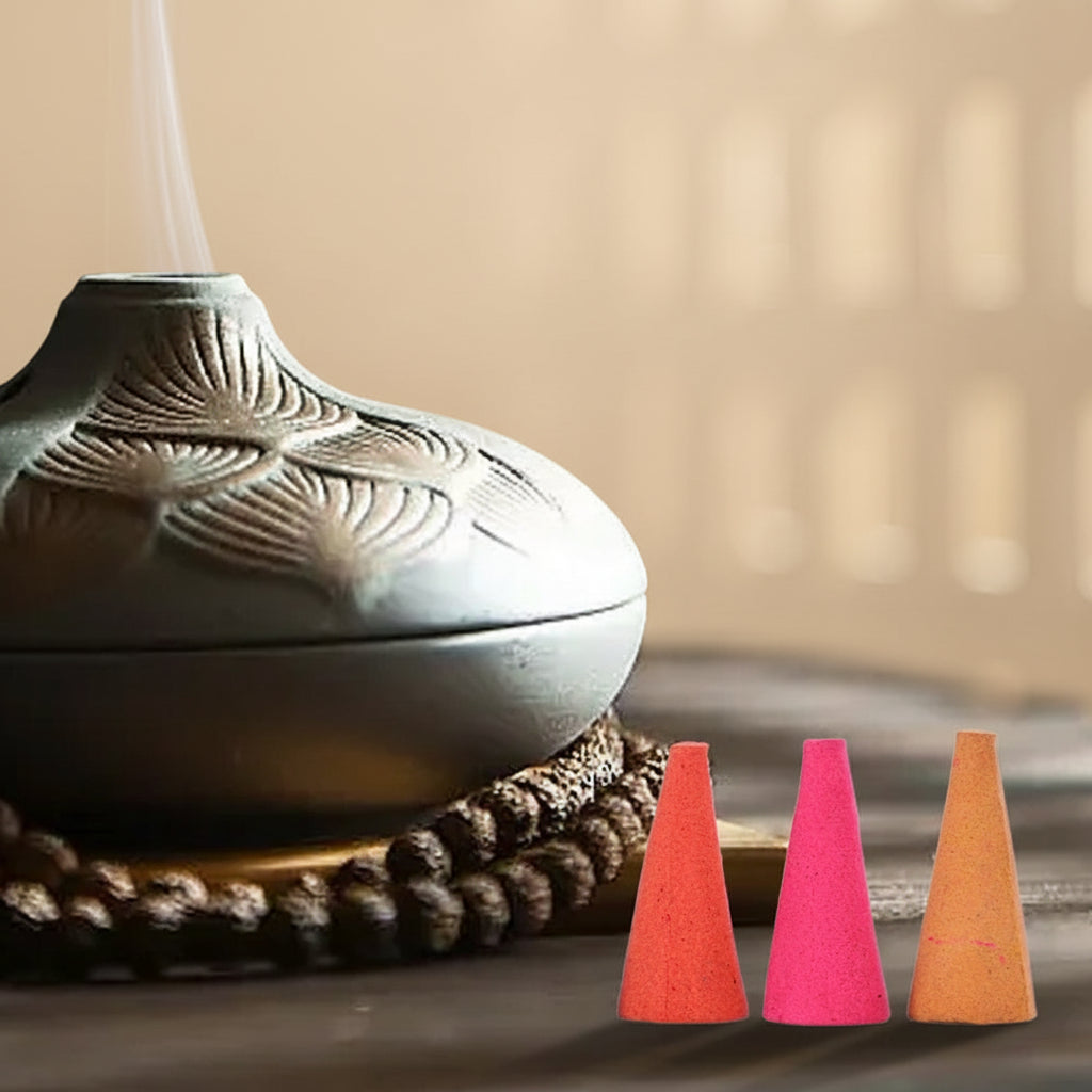 Ceramic incense burner with smoke and three colored cones on a blurred background