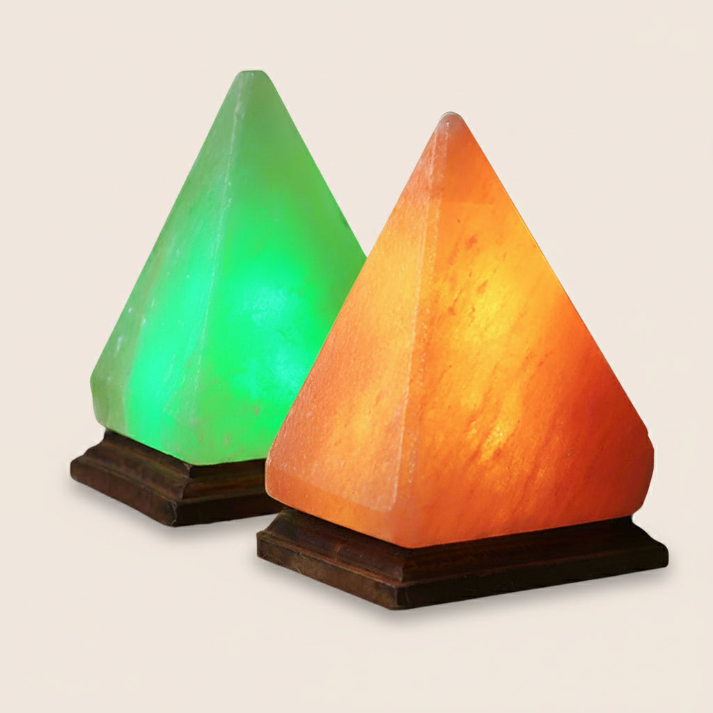Two pyramid-shaped salt lamps, one green and one orange, on a textured surface with a dark background.